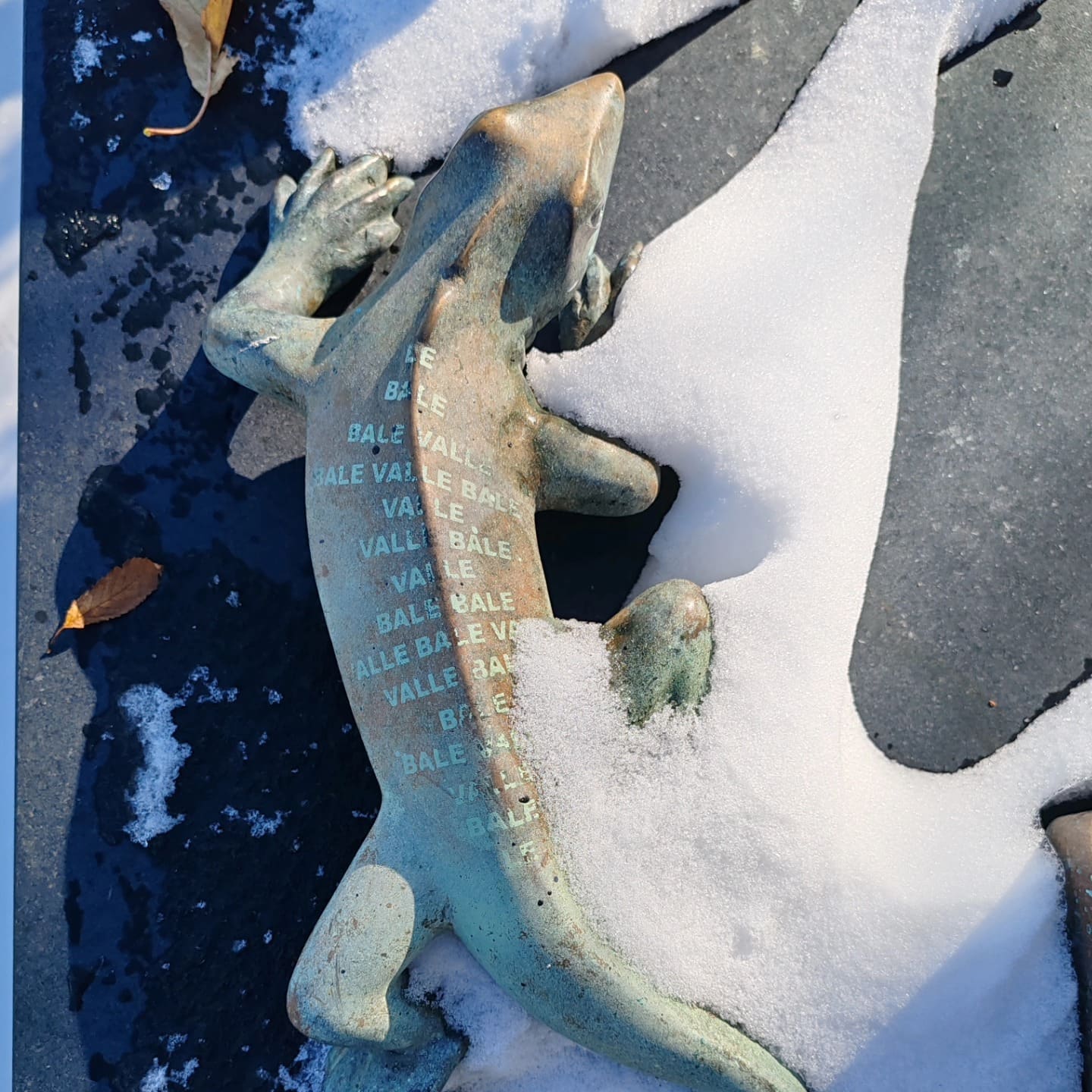 Bronze lizard sculpture resting in snow