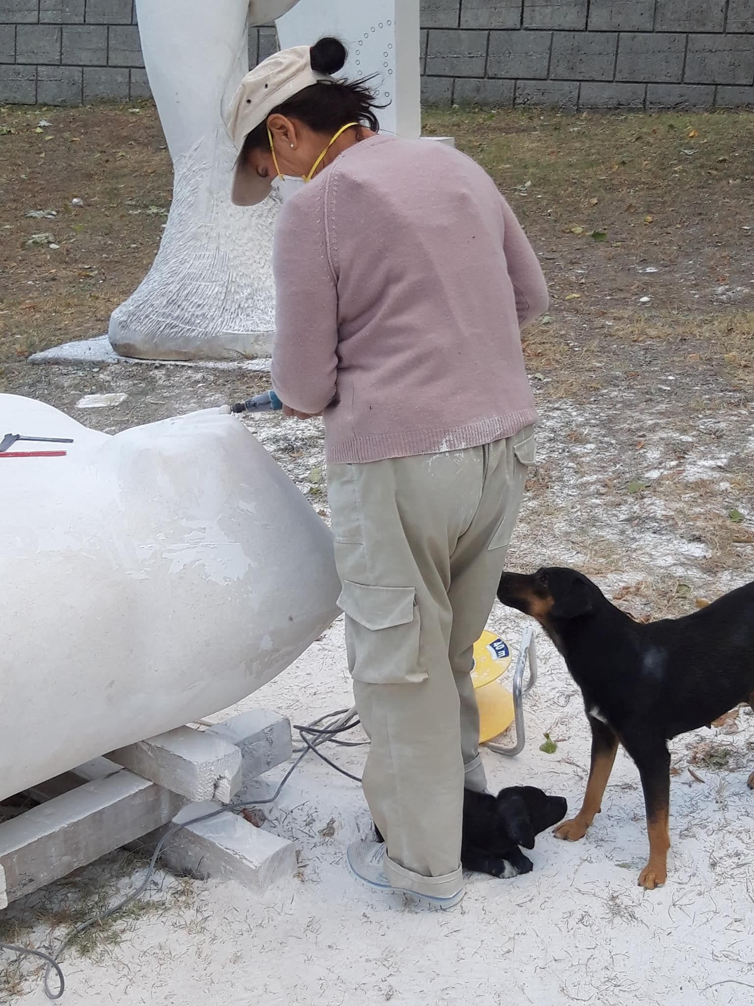 Marina Stoponja carving a white sculpture outdoors